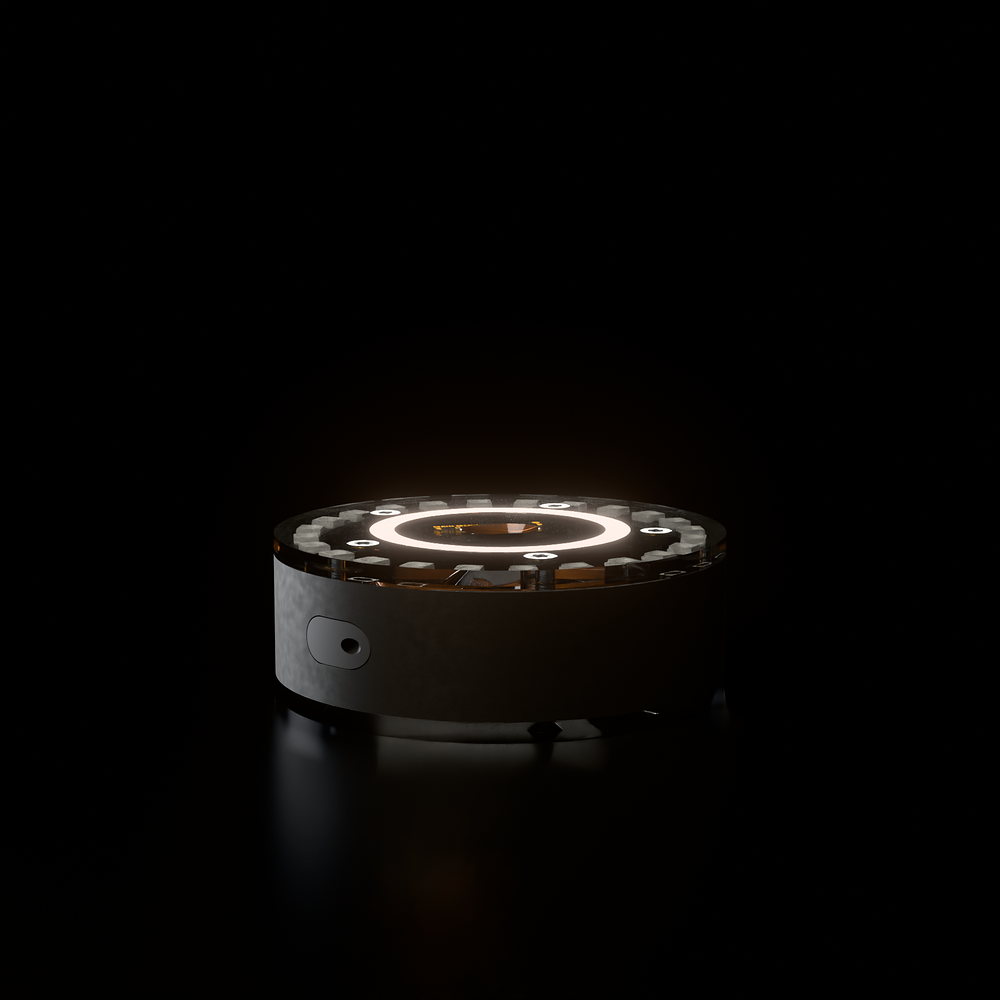 The Lumi pod: a 90 millimetre black disc with a clear acrylic top, standing in darkness.